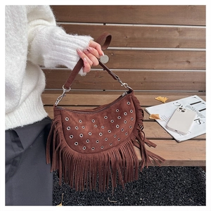 Detail of brown faux suede hobo bag featuring silver eyelets and long bohemian fringe