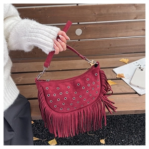 Détail du sac à franges en daim bordeaux avec œillets argentés sur fond d'automne