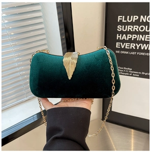Detail of dark green velvet evening clutch with golden leaf lock and metal chain strap