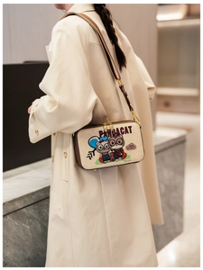 Detail of beige canvas crossbody bag with cute cartoon cat prints and brown leather trim