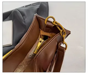 Close-up of premium brown leather texture with golden zipper and metal chain hardware