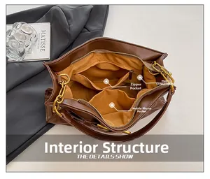 Detail view of brown shoulder bag interior showing main pocket, zipper pocket and phone slot