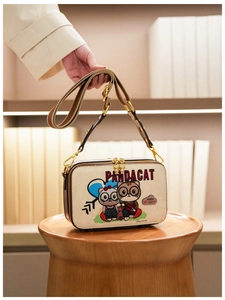 Detailed view of the cute cat cartoon print and gold double zipper on a small square bag