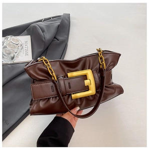 Detail of dark brown leather cloud bag with oversized gold buckle and thick chain strap