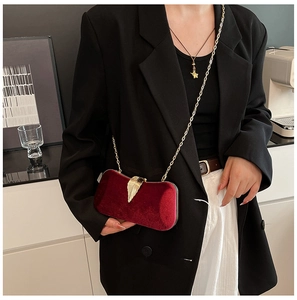 Burgundy velvet evening bag with gold leaf clasp and chain strap detail on model