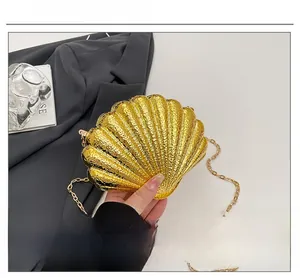 Détail du sac de soirée doré en forme de coquillage avec texture ondulée et chaîne métal