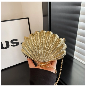 Gros plan d'une pochette de soirée dorée en forme de coquillage avec finition métal et chaîne