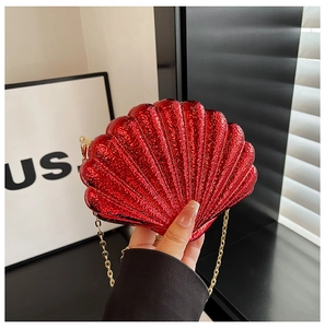 Détail d'une pochette de soirée rouge métallisé en forme de coquillage avec chaîne dorée