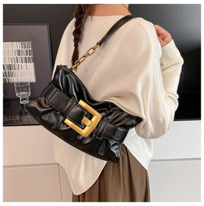 Detail of black pleated cloud bag featuring a large gold buckle and metal chain strap