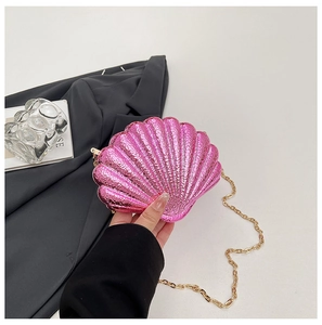 Détail d'un sac de soirée en acrylique rose en forme de coquillage avec chaîne dorée brillante