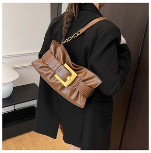Close-up of brown ruched shoulder bag with gold square buckle and chain strap detail