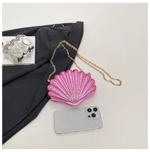 Détail du sac coquille rose fuchsia avec chaîne dorée et smartphone pour échelle