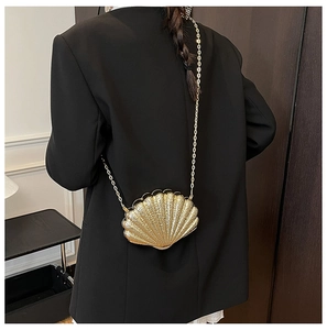 Détail de la pochette dorée en forme de coquillage portée sur une veste de costume