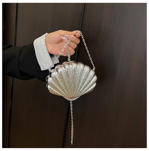 Détail de la pochette de soirée argentée en forme de coquillage avec texture brillante