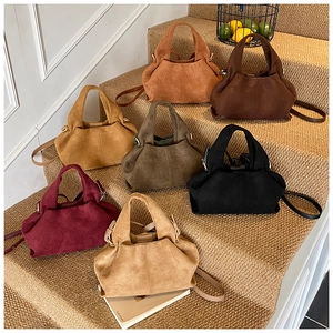 Collection of suede crossbody bags in various autumn colors displayed on steps