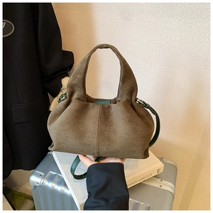 Detailed texture of brown suede tote bag with green leather shoulder strap in daily scene