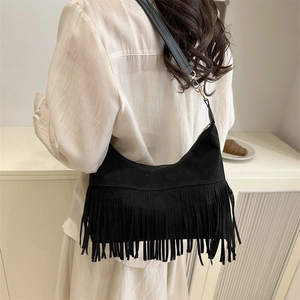 Minimalist black crescent bag with fringe on a model in a modern interior setting