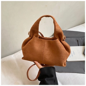 Detail view of brown suede cloud-shaped handbag with soft pleats and gold metal buckle