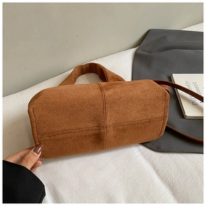 Detailed view of the cross-stitched bottom and suede texture of a vintage brown handbag
