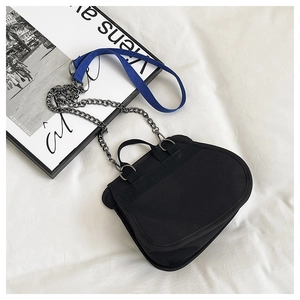 Close-up of black canvas bag featuring a bright blue strap and metal chain details