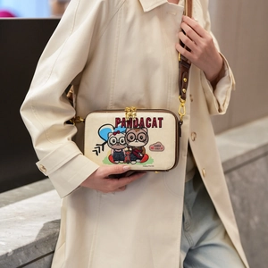 Japanese style cartoon cat crossbody bag in beige worn by a model in a trench coat