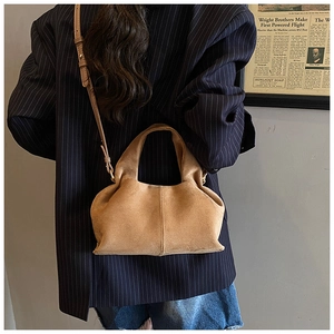 Brown suede bucket bag with pleated texture styled on a navy blue pinstripe blazer