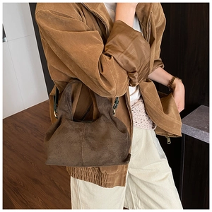 Detail of dark brown matte bucket bag showing soft pleated texture and metal buckle