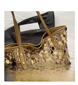 Close-up of golden sequined tote bag featuring round paillettes and leather handles