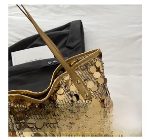Close-up of golden sequin tote bag detailing with round metallic disks and leather handle