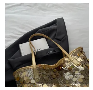 Close-up of golden sequin tote bag texture with slim straps and elegant metallic finish