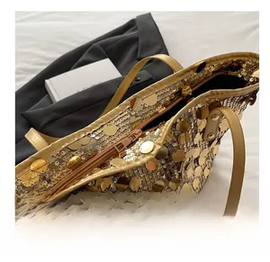 Detail view of the smooth metallic zipper closure on the golden sequined tote bag