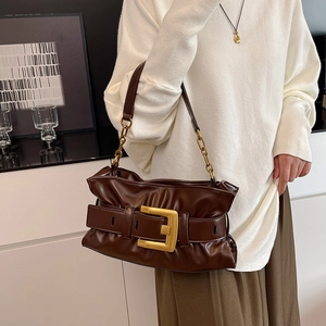Brown pleated cloud bag with large gold buckle and metal chain strap on model