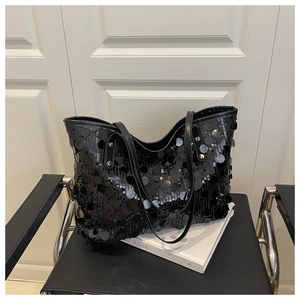 Détail de grandes paillettes noires et rivets dorés sur un grand sac cabas élégant