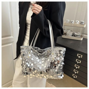 Close-up of silver sequin tote bag with metallic texture and leather handle strap