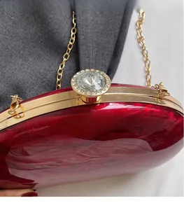 Detail of red marble acrylic clutch with gold hardware and rhinestone clasp