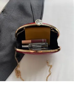 Macro view of dark red acrylic evening bag interior with gold chain and rhinestone clasp