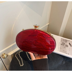 Detail of red marble acrylic evening clutch with gold metal frame and crystal clasp