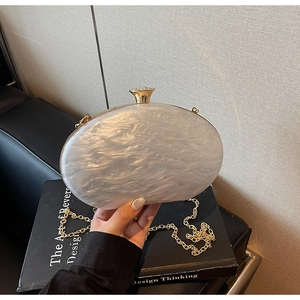 Detail of white marble acrylic clutch with gold chain and crystal clasp closure