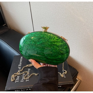 Detail of emerald green acrylic clutch featuring marble texture and gold gemstone clasp