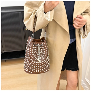 Dettagli della borsa a secchiello in pelle marrone con borchie e catena di perle