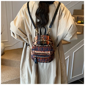 Mini-Plüschrucksack mit geometrischem Muster und Lederriemen an einem Modell
