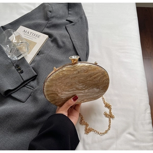Detail of marble pattern acrylic clutch with crystal clasp and golden chain strap