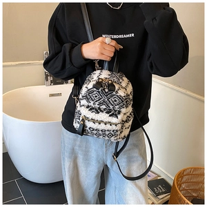 Détail d'un mini sac à dos en peluche avec motif géométrique noir et blanc et zips dorés