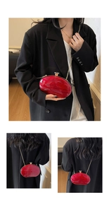 Detail of red marble acrylic oval evening bag with gold chain strap on black blazer
