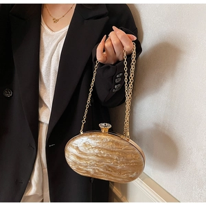 Detail of acrylic oval evening clutch featuring marble texture and gold chain strap