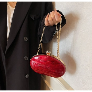 Detailed close-up of red marble acrylic clutch bag with gold chain and rhinestone clasp