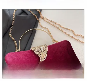 Detail of burgundy velvet clutch featuring ornate golden leaf clasp and metal handle