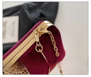 Detail of burgundy velvet evening bag with gold floral metal hollow carving and chain