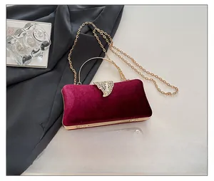 Macro view of burgundy velvet clutch with golden hollow metal clasp and chain