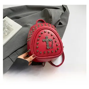 Detail of red PU leather mini backpack with silver rivets and vintage cross pendant